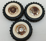 Three original Structo truck tires with white walls and hubs.