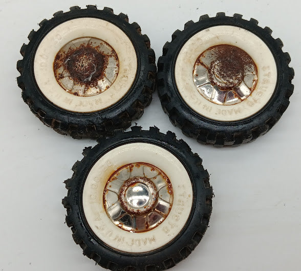 Three original Structo truck tires with white walls and hubs.