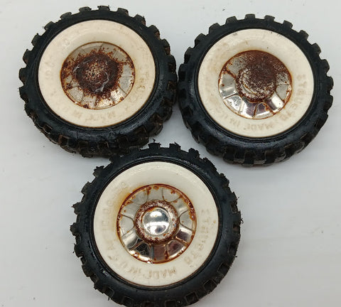 Three original Structo truck tires with white walls and hubs.